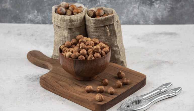 Bowl of organic hazelnut kernels on cutting board with shelled hazelnuts Bowl of organic hazelnut kernels on cutting board with shelled hazelnuts. High quality photo