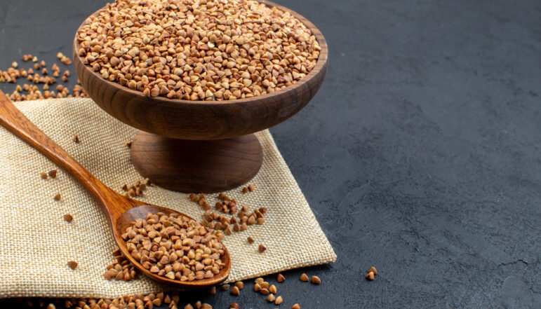 front-view-brown-buckwheat-inside-plate-with-pair-spoons-dark-background front-view-brown-buckwheat-inside-plate-with-pair-spoons-dark-background