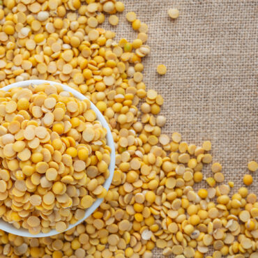 Raw soybeans in a white glass placed on a floor.